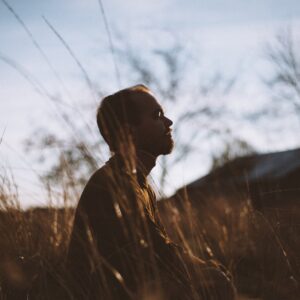 silhouette of man sitting on grass field at daytime