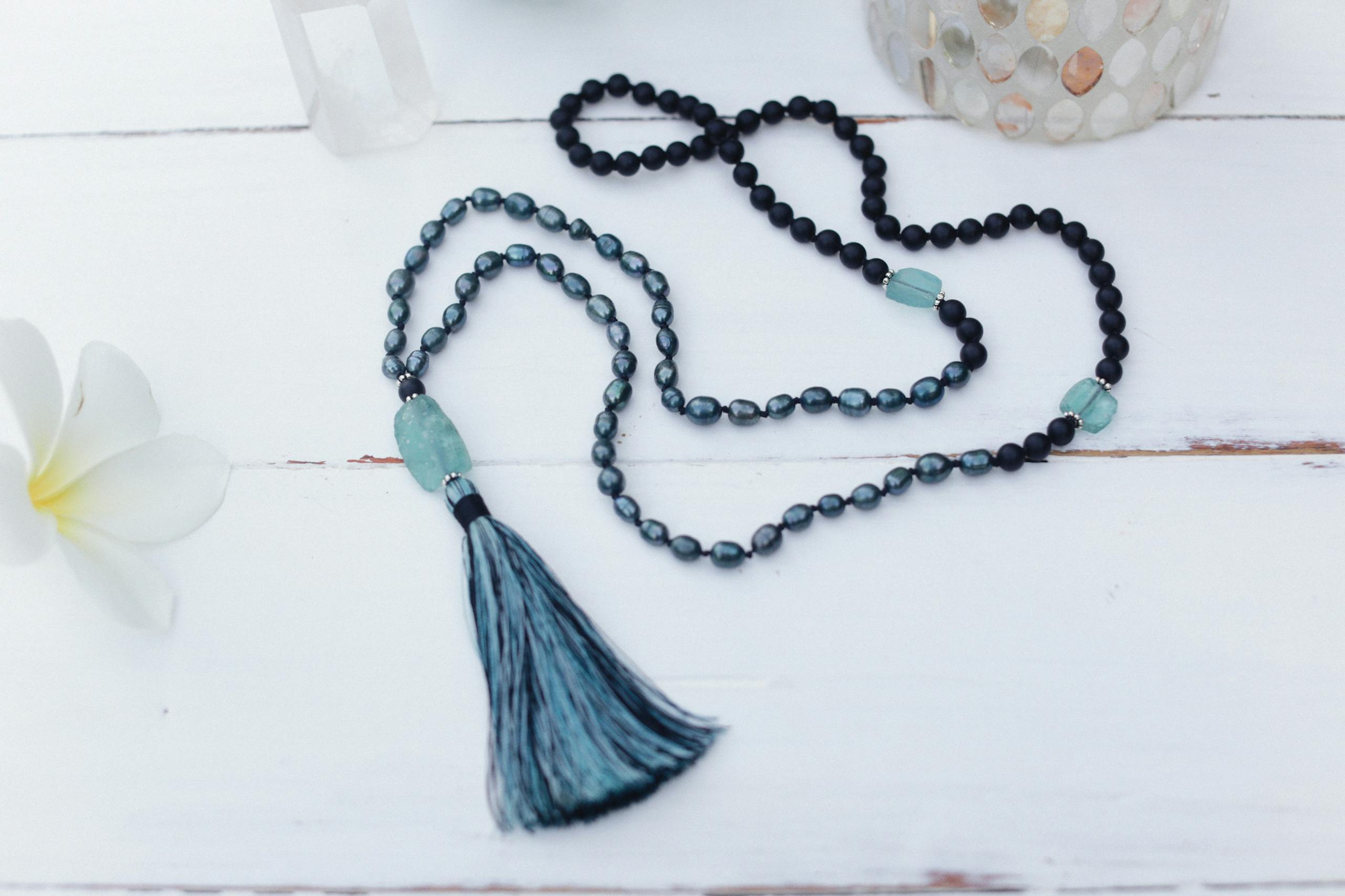 Close-up of a handmade mala beads necklace with a tassel on a white background, ideal for meditation.